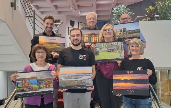  – Freuen sich über den Fotokalender 2025: BM Björn Steinbach (oben links), DruckerJürgen Schweikert (oben rechts) und Mitglieder des Fotoclubs Obersulm. Foto: Gemeinde